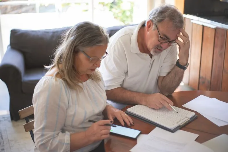 An elderly couple reviewing information together at their kitchen table